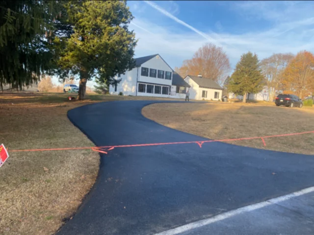 Curving new asphalt driveway up to a white colonial, South State Paving, Southern Maryland