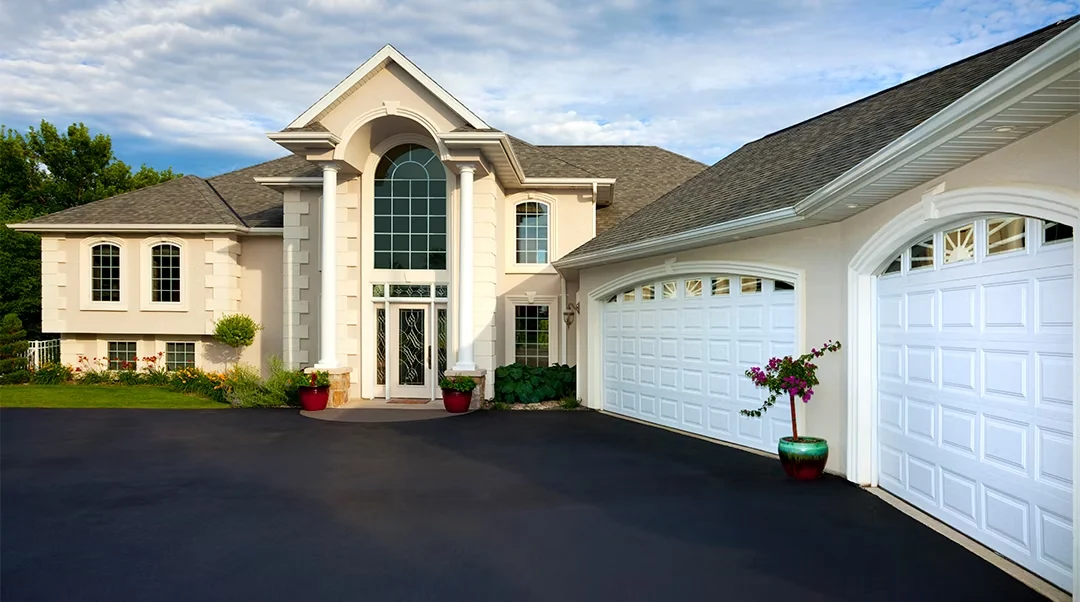 Fresh black driveway at a two-story home with double white garage doors, South State Paving, Southern Maryland