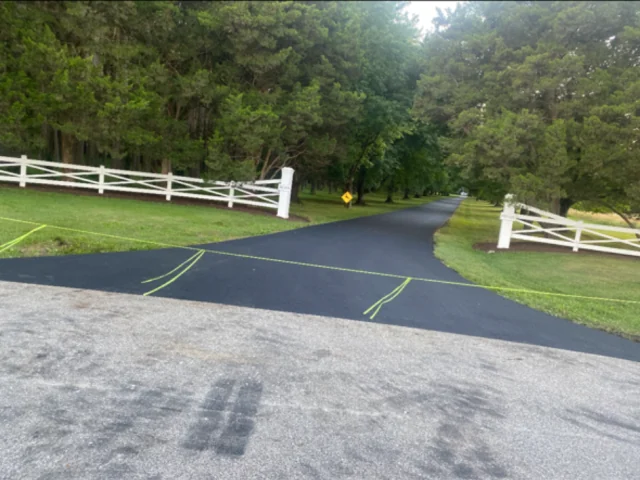 New asphalt farm lane entrance between white fence posts, South State Paving, Southern Maryland