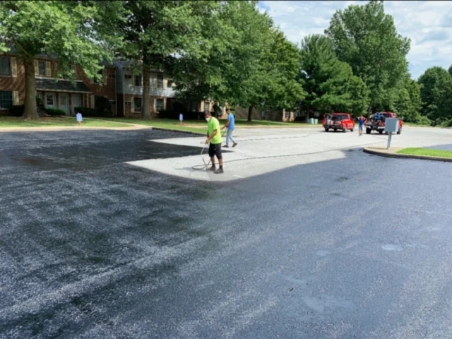 Sealcoating a commercial lot around a concrete pad, South State Paving, Southern Maryland