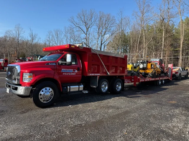 South State Paving dump truck hauling the paver to a job